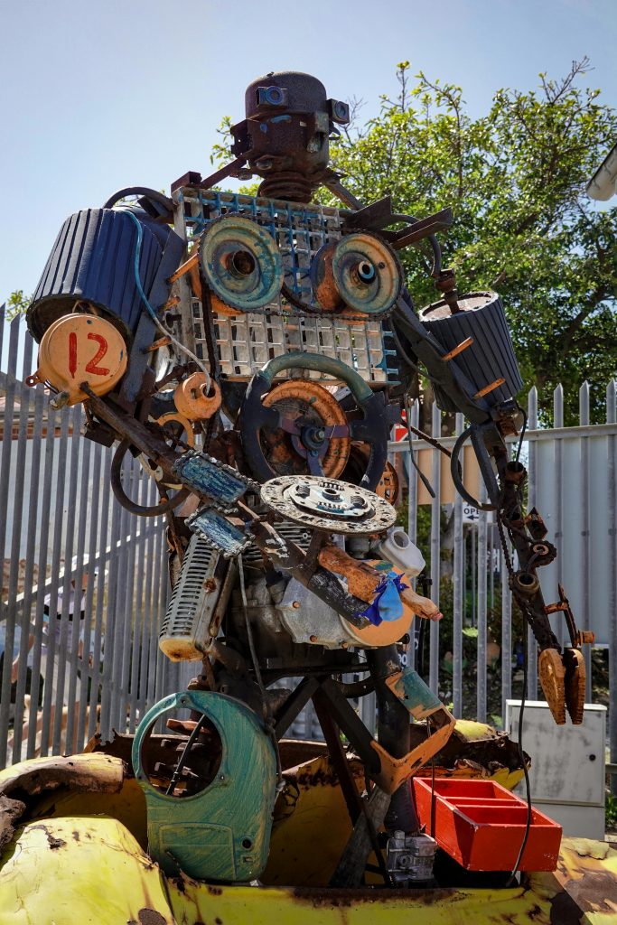 Intricate robot sculpture crafted from recycled metal and scrap materials outdoors.